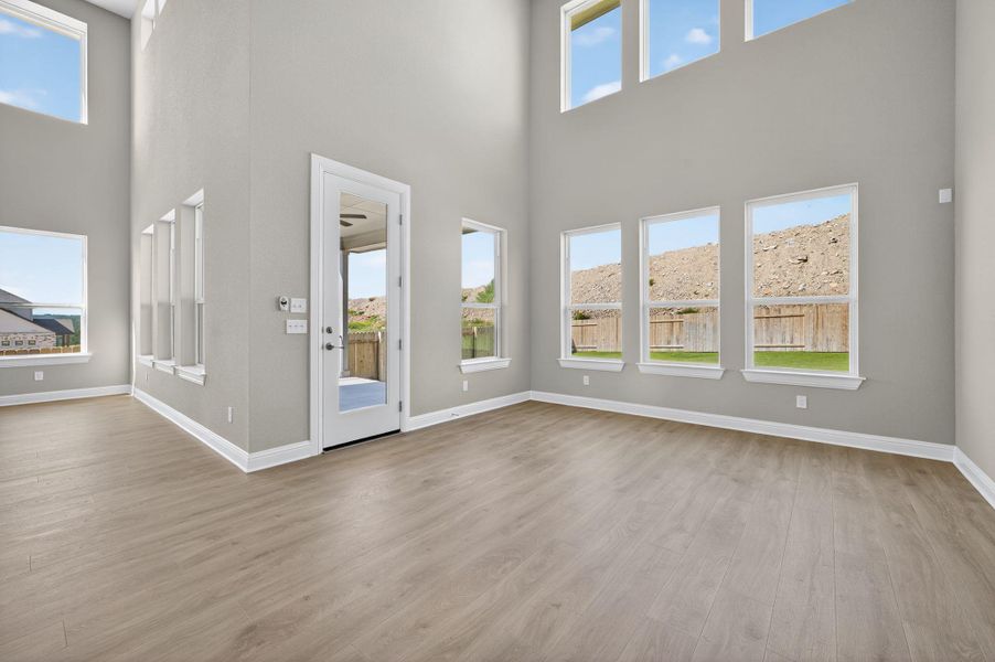 Unfurnished living room with a towering ceiling, light wood-style flooring, and plenty of natural light