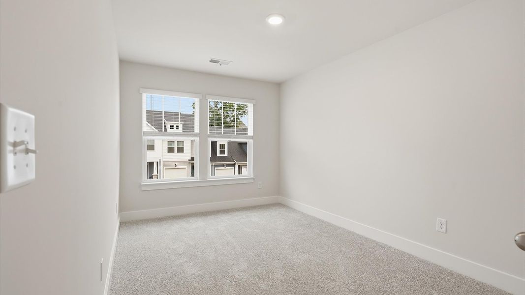 Highly functional bedroom with large windows, carpeted flooring, and tasteful finishes throughout at Aspen Ridge