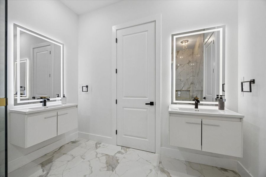 This modern bathroom features dual vanities with sleek, illuminated mirrors and elegant marble-patterned tile flooring, creating a luxurious and contemporary feel. This modern bathroom features dual vanities with sleek, illuminated mirrors and elegant marble-patterned tile flooring, creating a luxurious and contemporary feel.