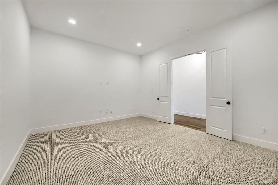 Versatile interior space featuring light-colored walls, recessed lighting, and soft carpeting