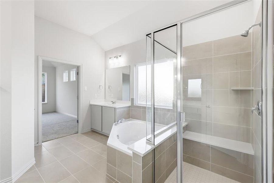 Full bathroom featuring a garden tub, lofted ceiling, a stall shower, light tile patterned flooring, and plenty of natural light