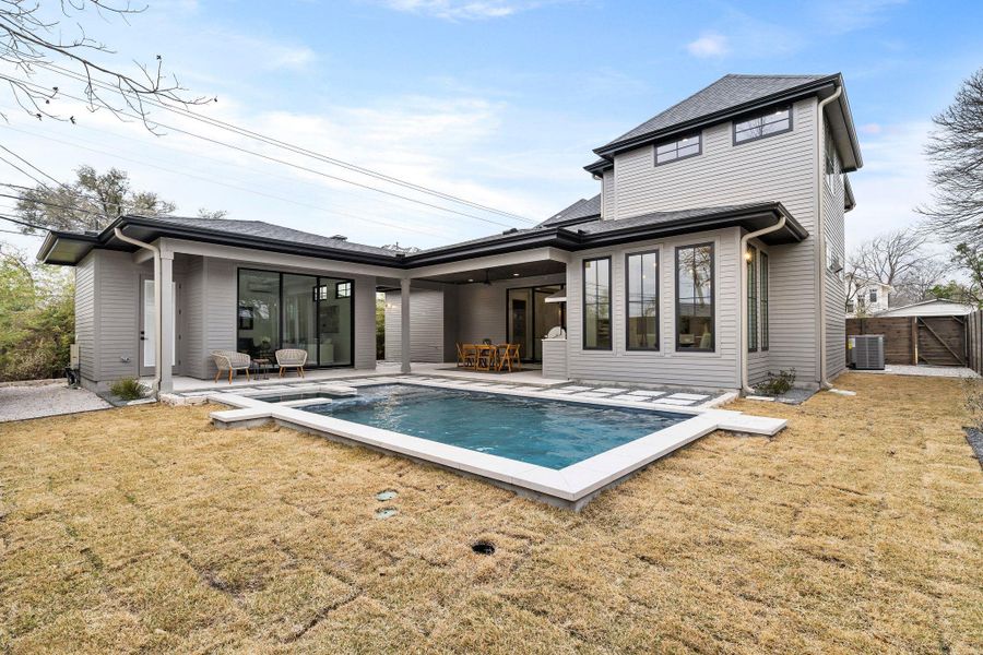 Back of property featuring cooling unit, a yard, a patio area, and an outdoor pool