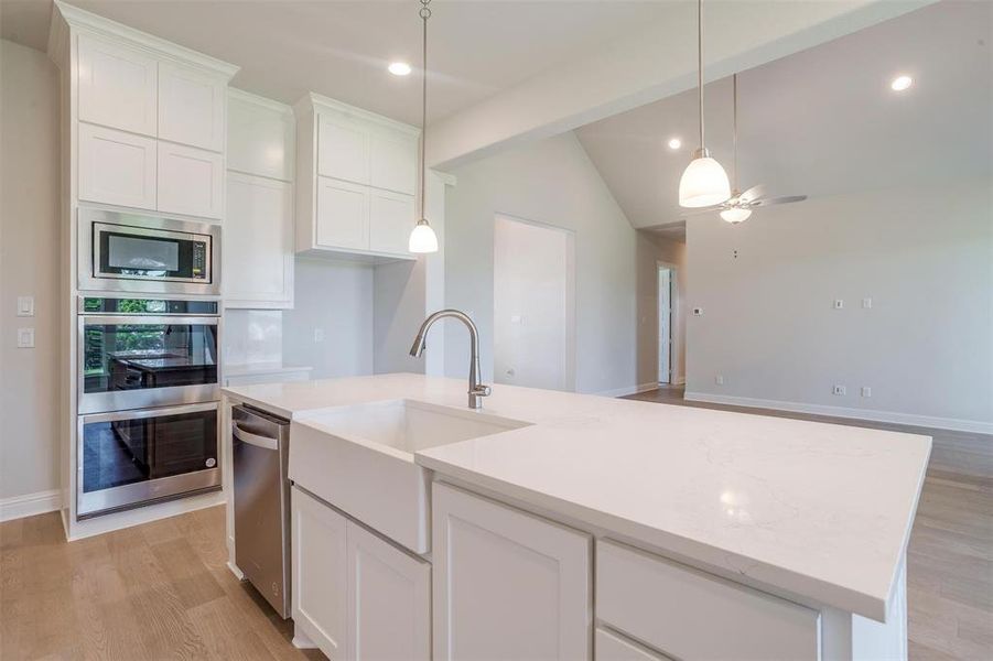 Kitchen featuring light wood-type flooring, a center island with sink, appliances with stainless steel finishes, and lofted ceiling