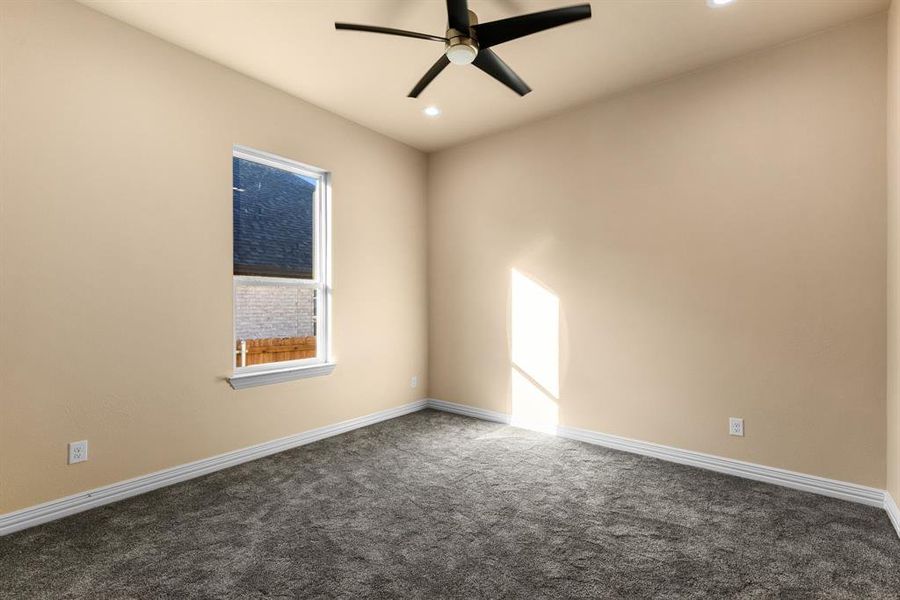 Unfurnished room with ceiling fan and dark colored carpet