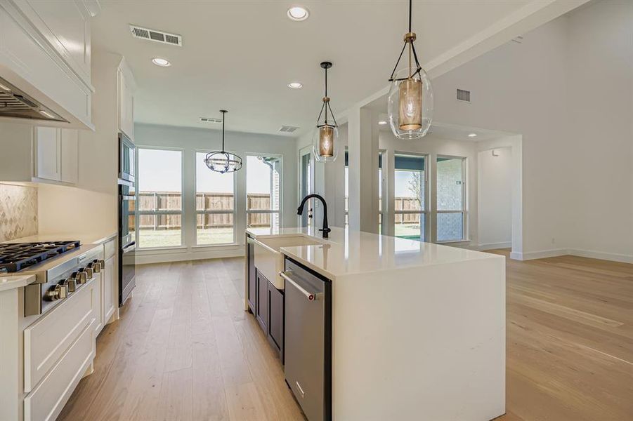 Kitchen featuring light wood-style floors, stainless steel appliances, white cabinets, custom exhaust hood, and light countertops