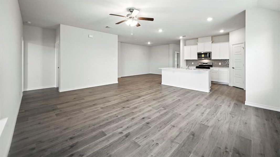 Open-concept living space with wood-finish flooring, recessed lighting, and a ceiling fan Open-concept living space with wood-finish flooring, recessed lighting, and a ceiling fan