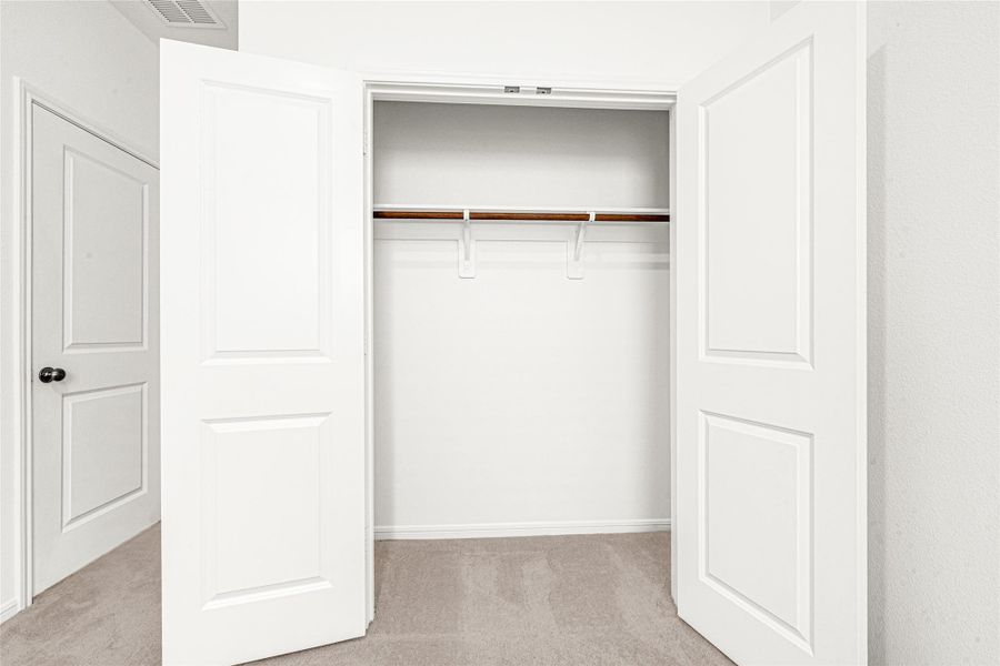 Another spacious walk-in closet featuring built-in shelving and ample hanging space.