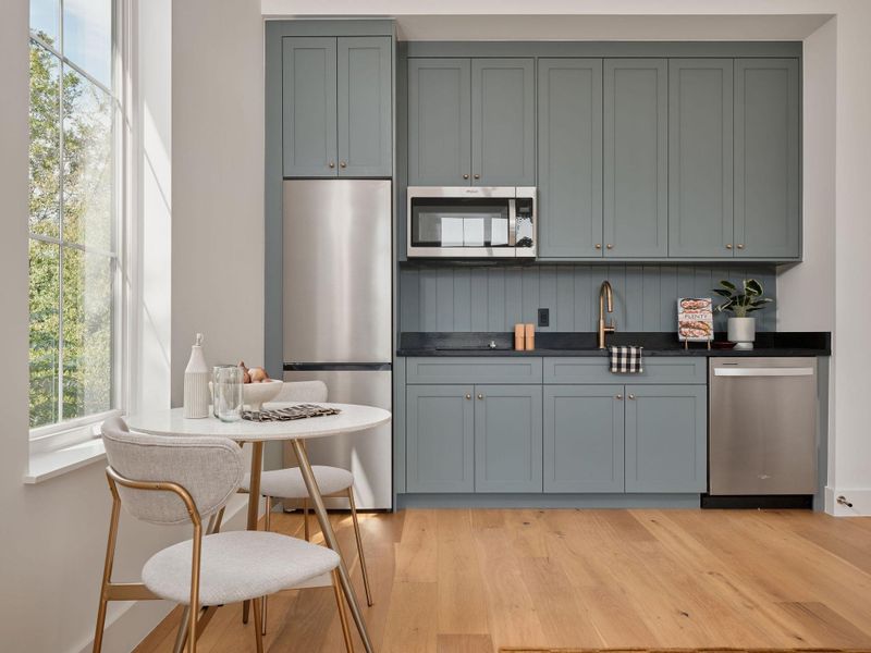 Kitchen featuring gray cabinets, appliances with stainless steel finishes, light wood-type flooring, and dark stone counters Kitchen featuring gray cabinets, appliances with stainless steel finishes, light wood-type flooring, and dark stone counters