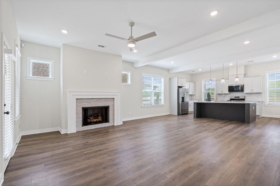 Unfurnished living room with a ceiling fan, beam ceiling, dark wood-type flooring, a stone fireplace, and recessed lighting Unfurnished living room with a ceiling fan, beam ceiling, dark wood-type flooring, a stone fireplace, and recessed lighting
