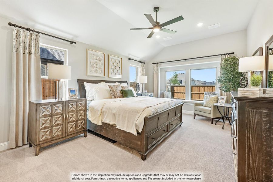Master bedroom with vaulted ceiling, ceiling fan, dark wood bed frame, carpet flooring, and large windows with natural light.