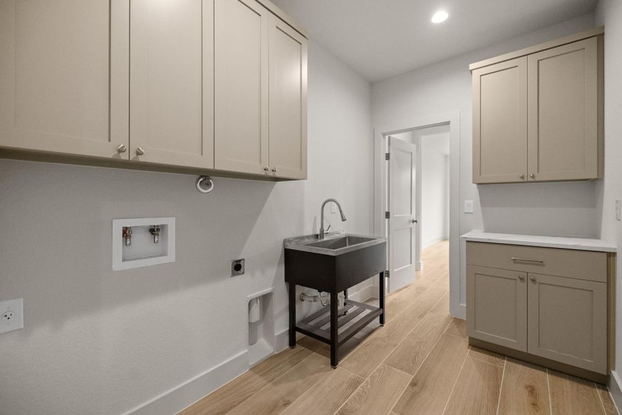 Functional laundry room featuring abundant cabinet storage and a utility sink.