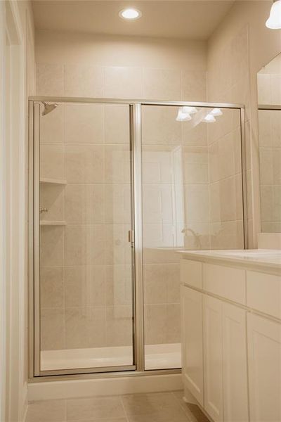 Bathroom featuring tile patterned floors, vanity, and a shower with shower door