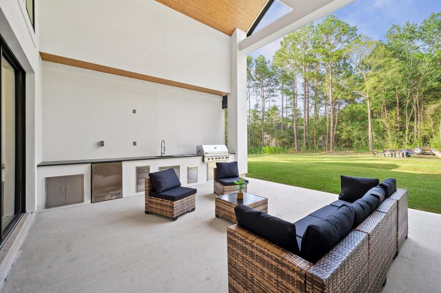 Covered outdoor living area featuring vaulted wood ceiling accents and fully equipped outdoor kitchen.