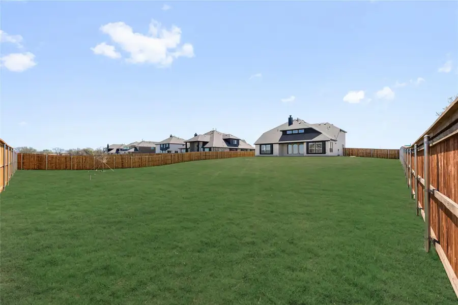 Large backyard with green grass lawn, wood privacy fence, and home visible in background Large backyard with green grass lawn, wood privacy fence, and home visible in background