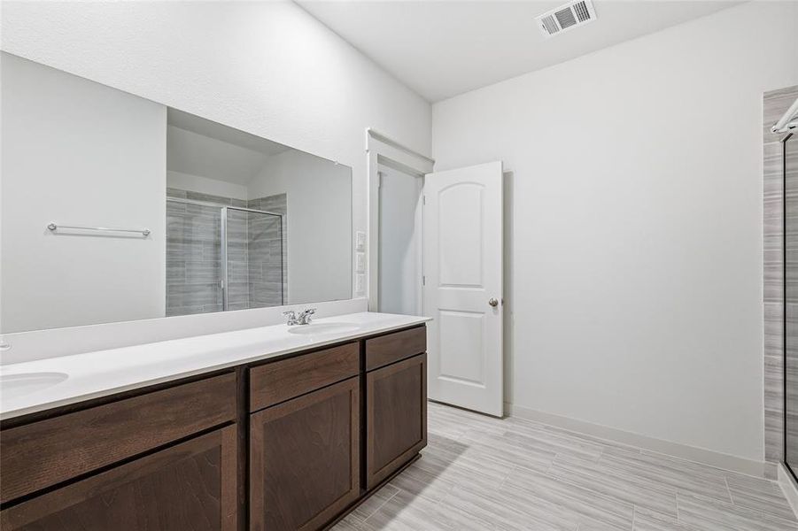 Bathroom with a shower stall, double vanity, and wood finish floors Bathroom with a shower stall, double vanity, and wood finish floors