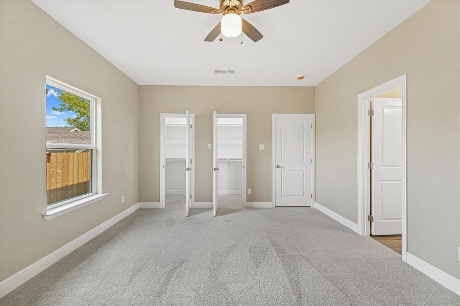 Unfurnished bedroom with two closets, light colored carpet, and ceiling fan Unfurnished bedroom with two closets, light colored carpet, and ceiling fan