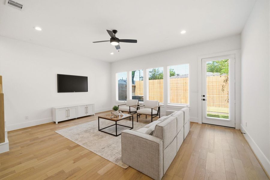 Spacious living area overlookingthe private backyard withoversized windows and seamlessindoor-outdoor flow. (Photo of a previous build, similar finishes.)