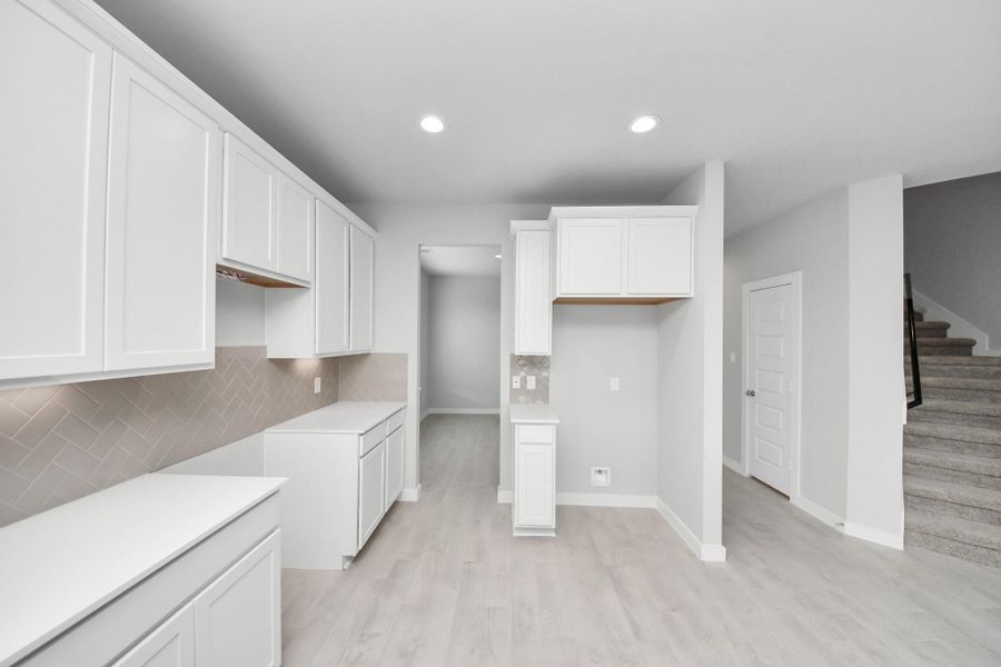 Discover another perspective of this stunning kitchen, generously appointed with an abundance of counter space. Sample photo of completed home with similar floor plan. Actual colors and selections may vary. Discover another perspective of this stunning kitchen, generously appointed with an abundance of counter space. Sample photo of completed home with similar floor plan. Actual colors and selections may vary.