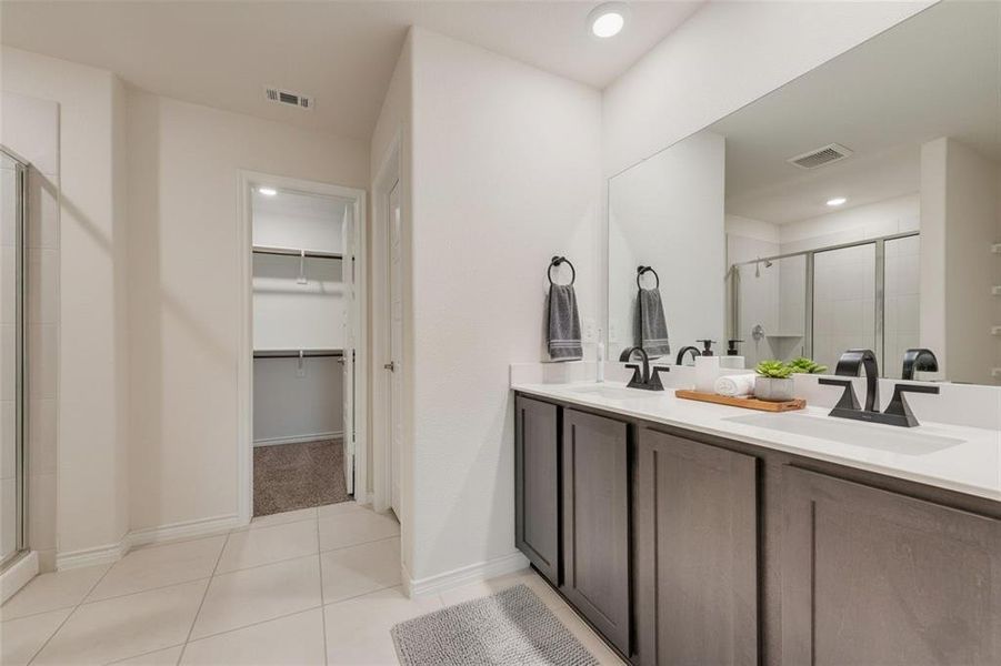 Bathroom with light tile patterned floors, a stall shower, double vanity, and a spacious closet