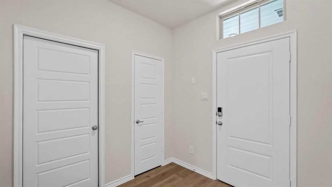 Foyer showcasing a crisp white entry door with an electronic lock and an overhead transom window
