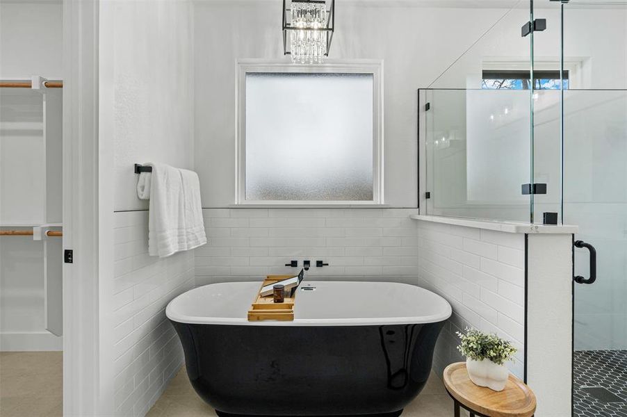 Full bath with a stall shower, a soaking tub, tile patterned flooring, and tile walls