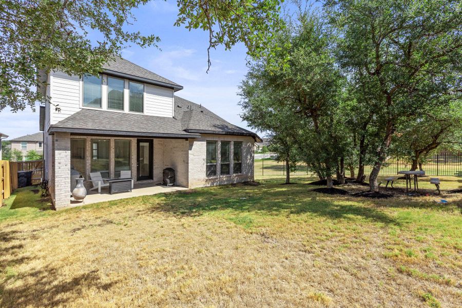 Mature shade trees and a level lawn surround the rear of this two-story home.