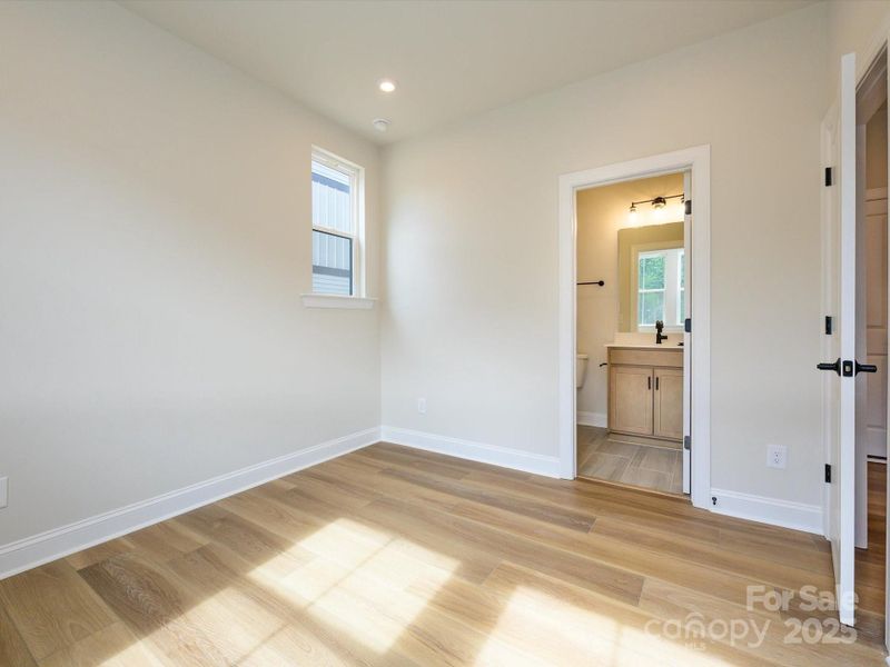 Sneak peak into first floor en suite guest bath with modern floor tile and walk-in shower.