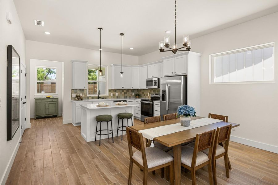 An open concept kitchen and dining area feature light wood-look flooring and stainless steel appliances. An open concept kitchen and dining area feature light wood-look flooring and stainless steel appliances.