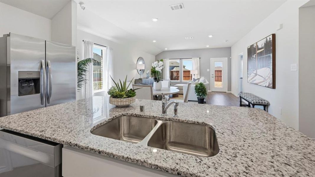 Kitchen featuring a double stainless steel sink, a stainless steel refrigerator, and granite countertops
