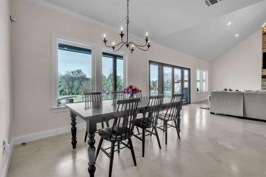 Dining room with finished concrete floors, hanging lights, and vaulted ceiling Dining room with finished concrete floors, hanging lights, and vaulted ceiling