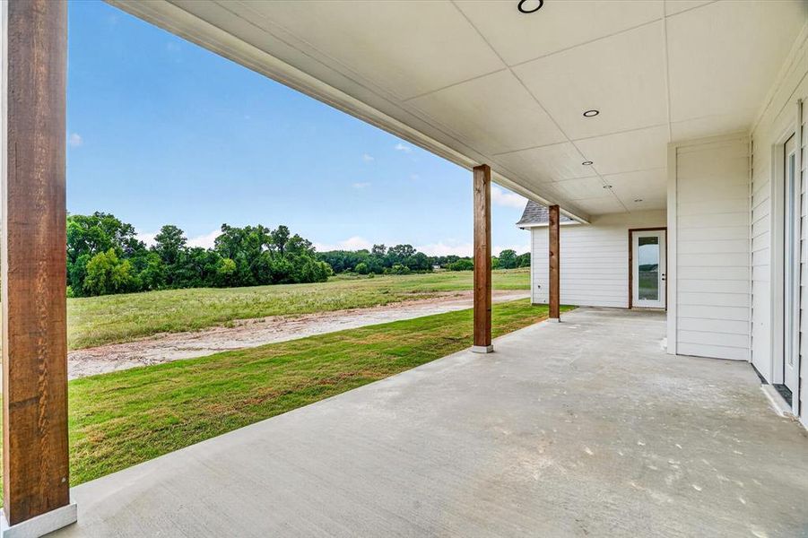 Covered concrete patio featuring exposed wood support beams and recessed lighting