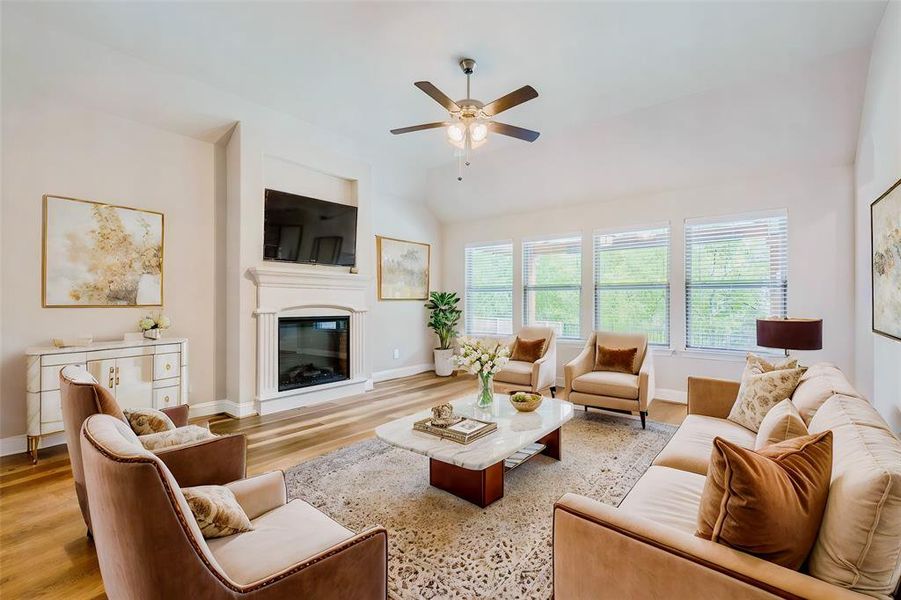 Living room featuring ceiling fan, vaulted ceiling, and light hardwood / wood-style flooring