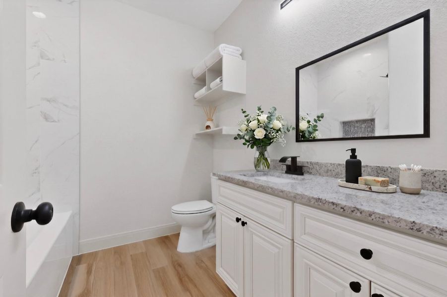 White vanity with black hardware, a speckled countertop, and an undermount sink White vanity with black hardware, a speckled countertop, and an undermount sink