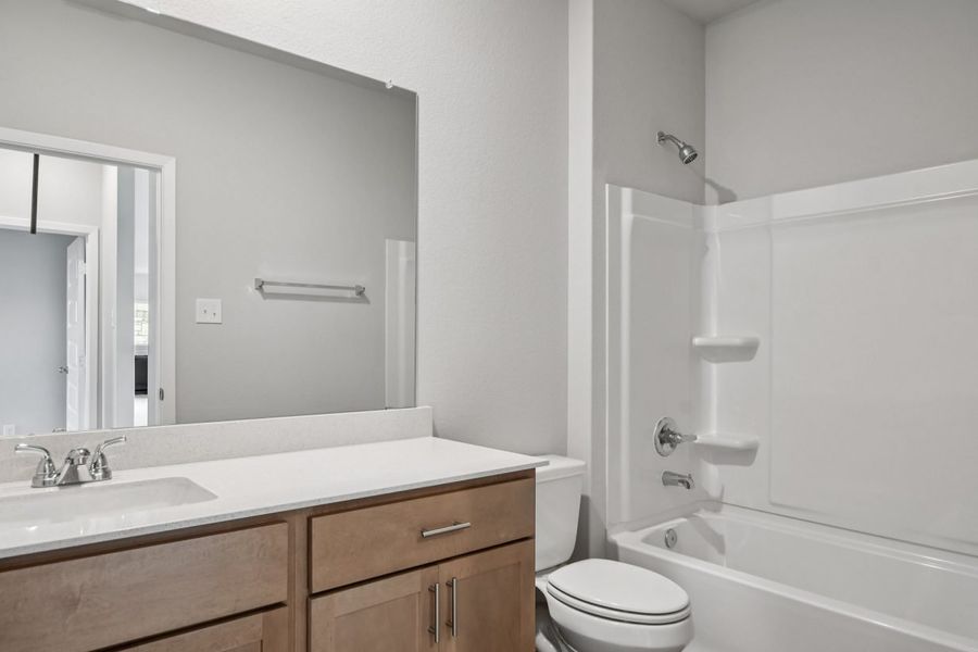 Image of a bathroom with brown cabinets, a large mirror and white souble vanity
