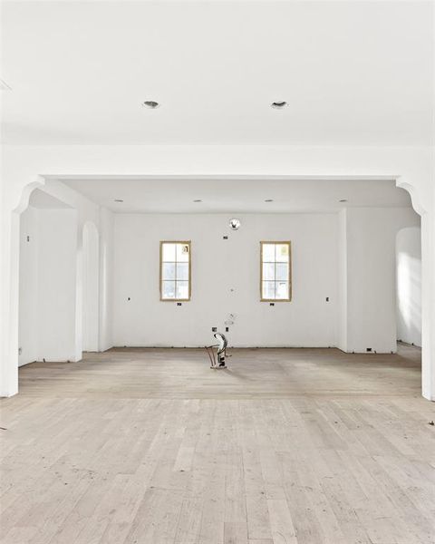 Unfurnished room with arched walkways, healthy amount of natural light, and light wood finished floors