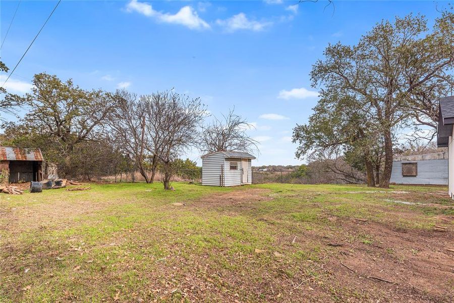 View of green lawn featuring a storage shed