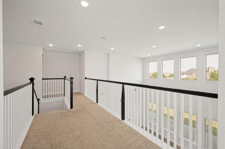 Spacious upper-level landing featuring neutral carpeting and crisp white walls