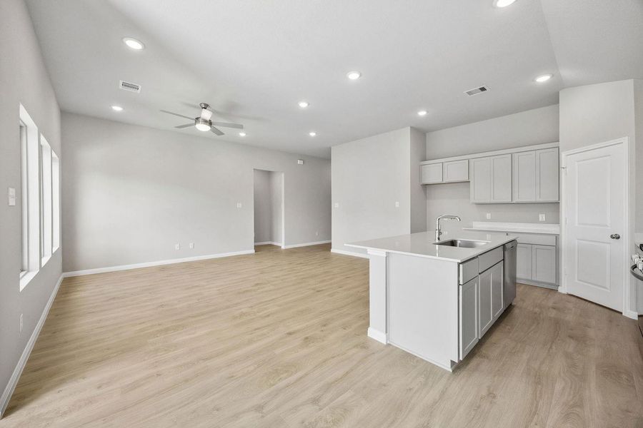An open concept living area seamlessly connects with a bright kitchen island and clean cabinetry.
