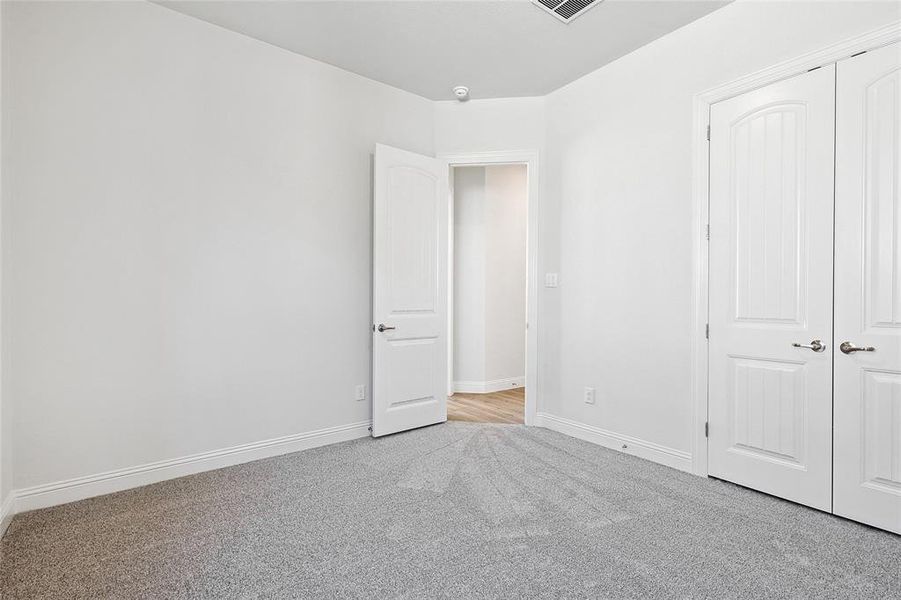 Unfurnished bedroom with light carpet and a closet