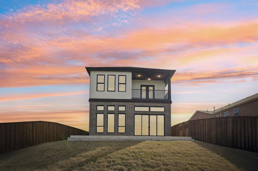 Backyard showcasing downstairs patio, upstairs shared balcony, and the abundance of soaring floor-to-ceiling windows.