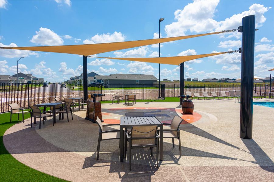 Outdoor amenity area featuring multiple shade sails, aggregate paving, and artificial turf