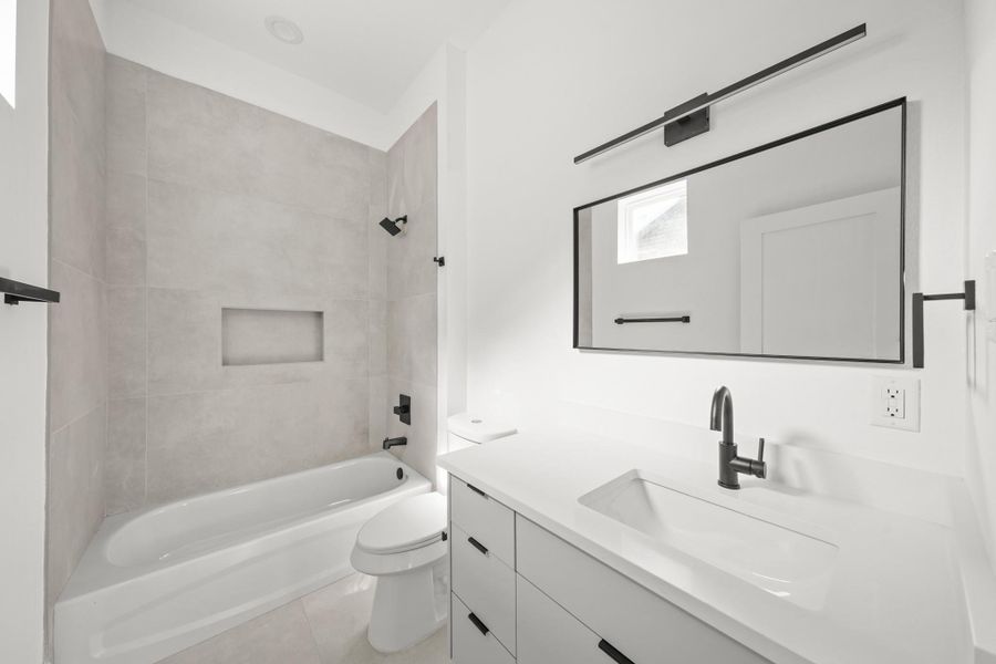 A sleek, modern bathroom featuring a floating vanity with an under mount sink and a black-framed mirror with a contemporary light fixture above. A sleek, modern bathroom featuring a floating vanity with an under mount sink and a black-framed mirror with a contemporary light fixture above.