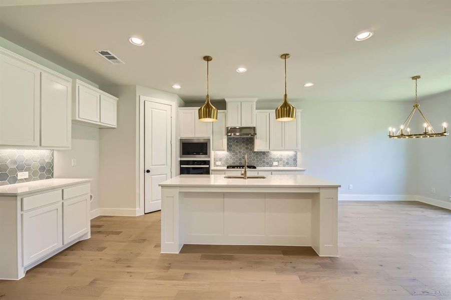 Kitchen with backsplash, white cabinetry, light countertops, recessed lighting, and a chandelier Kitchen with backsplash, white cabinetry, light countertops, recessed lighting, and a chandelier