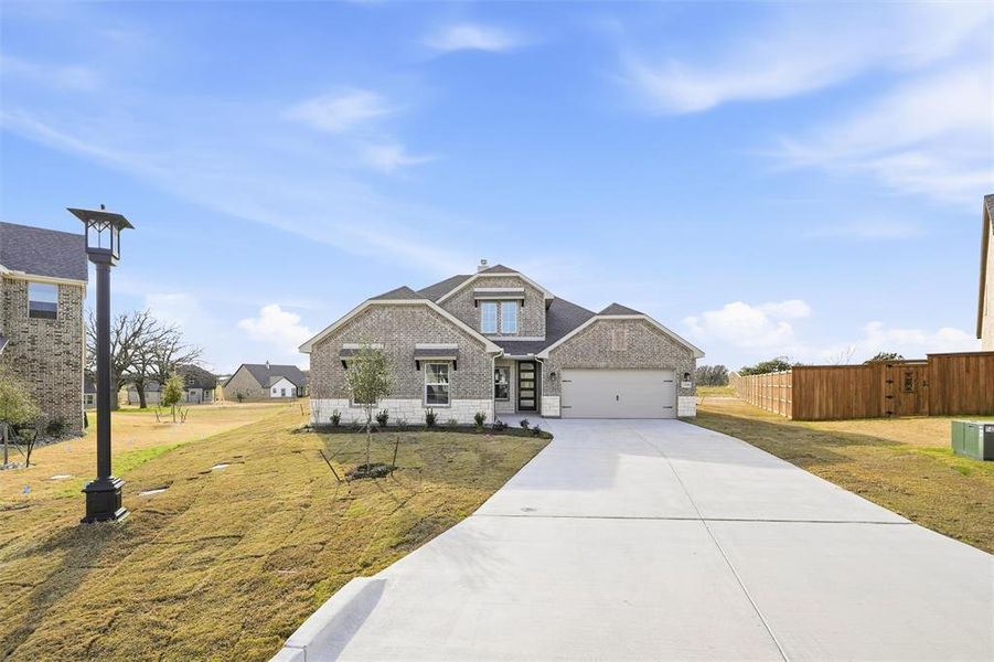 Craftsman-style house featuring driveway, brick siding, and an attached garage