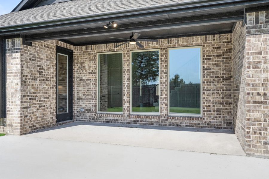 Covered back patio with ceiling fan, brick exterior, large windows, and concrete slab Covered back patio with ceiling fan, brick exterior, large windows, and concrete slab