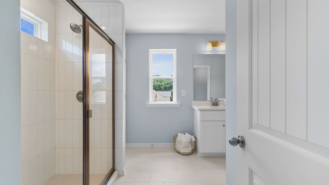Bright bathroom featuring modern design, quartz vanity tops, sleek finishes, and ample lighting.