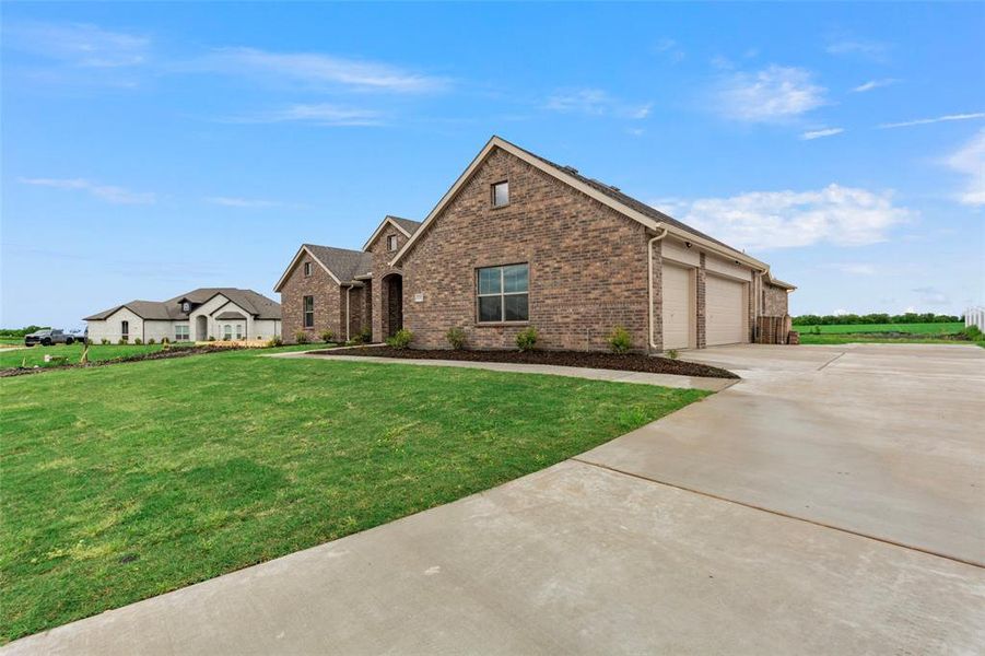 View of front of house featuring brick siding, concrete driveway, a front yard, and an attached garage