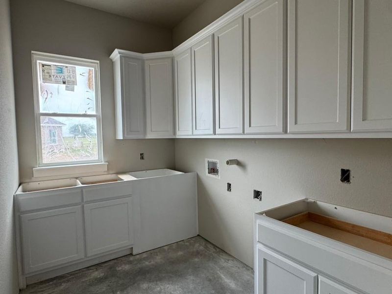 Utility area featuring white shaker-style cabinetry, a double-hung window, and neutral wall finishes