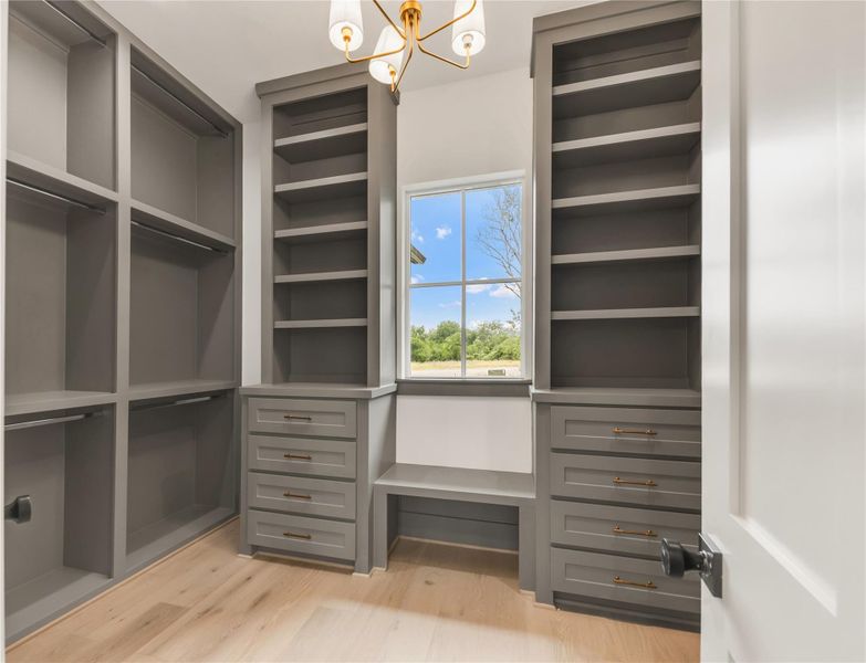 Walk in closet with hanging lights and light wood-type flooring