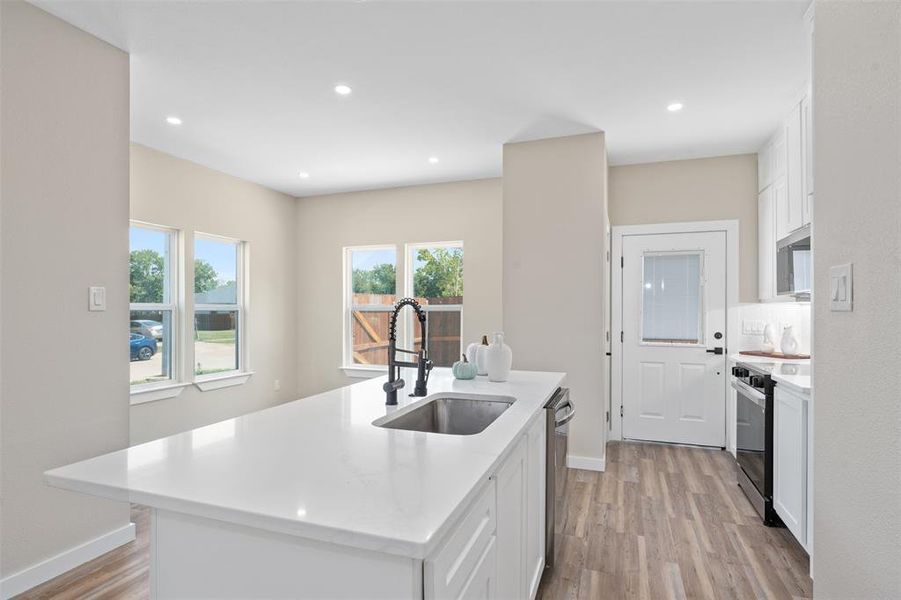 Kitchen featuring white cabinets, light wood-style floors, recessed lighting, a kitchen island with sink, and stainless steel appliances